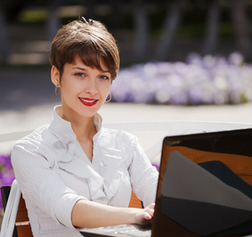 Young businesswoman with laptop at a sidewalk cafe