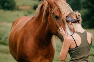 Young beautiful girl hugging horse at nature.